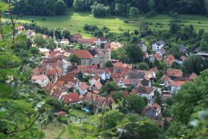 Blick auf den ländlichen Ortsteil Ziegenhain. Zu sehen ist eine Ortschaft mit dicht stehenden Häusern und roten Ziegeldächern. Der Ort ist umgeben von viel Grün (Wiesen, Bäumen und Sträuchern).