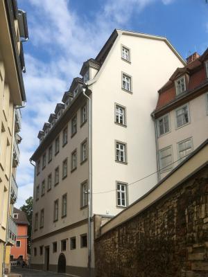 weißes Haus mit vielen Sprossenfenstern in einer engen Gasse