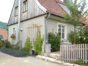 hellgrünes Haus mit weißen Fenstern, rotem Dach, holzverkleidetem Giebel und Fassadenbegrünung