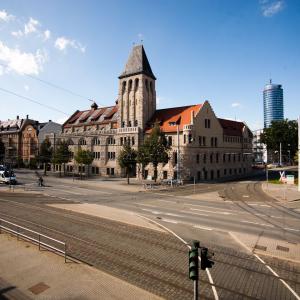 Blick vom Paradiesbahnhof auf das historische Volksbad und den JenTower mit blauem Himmel, im Vordergrund Straßenbahnschienen