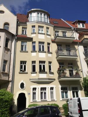 Haus mit heller Fassde, Fenster- und Balkonelementen vor blauem Himmel