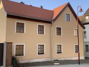 Haus mit rötlicher Fassade und Fenstern vor blauem Himmel, im Vordergrund eine Straße