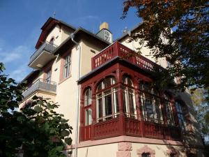 Haus mit rotem Wintergarten und darüberliegendem Balkon