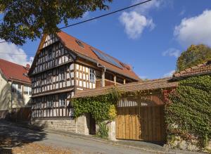 Saniertes Bauernhofensemble mit rotem Satteldach, neuer Fachwerkfassade und restauriertem Hoftor