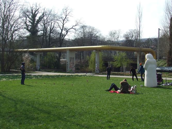 Man sieht eine Wiese, auf der mehrere Menschen spielen und sich ausruhen, das alles auf der Rasenmühleninsel Jena