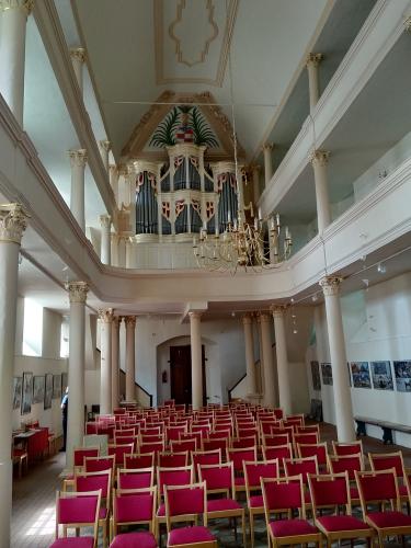 Inneres eines Kirchenschiffs mit Orgel und roten Stühlen