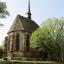 Kirche aus Natursteinen mit kleiner Mauer als Einfriedung